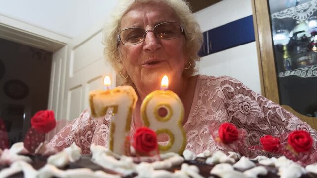 Smiling Grandmother Blowing Out Birthday Cake Candles