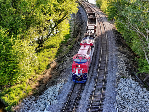 Savanna, Illinois May 10, 2026 CPKC 776 America 250 locomotive pulling  freight on parallel tracks through a lush green forest