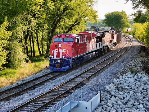 Savanna, Illinois May 10, 2026 CPKC 776 America 250 locomotive pulling  freight on parallel tracks through a lush green forest