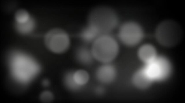 Abstract monochrome bokeh light particles pulsing on dark background, ideal for motion graphics, video overlays and cinematic background