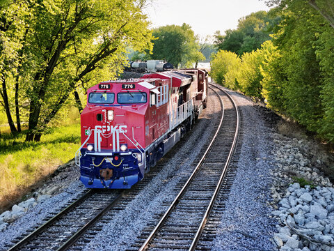 Savanna, Illinois May 10, 2026 CPKC 776 America 250 locomotive pulling  freight on parallel tracks through a lush green forest