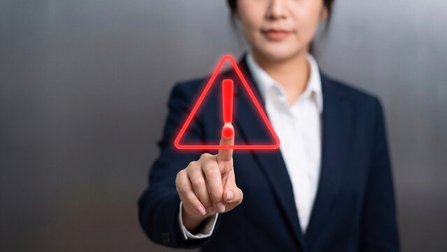 Businesswoman touching a warning triangle sign, Risk management, system error alert, or cybersecurity caution