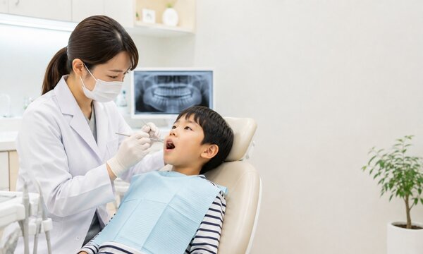 歯科医院で女性歯科医師の診察を受ける小学生の男の子と小児歯科の診療風景