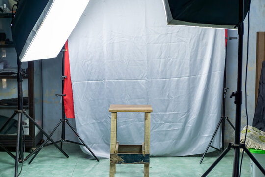 Empty photo studio setup with softbox lights wooden stool and backdrop