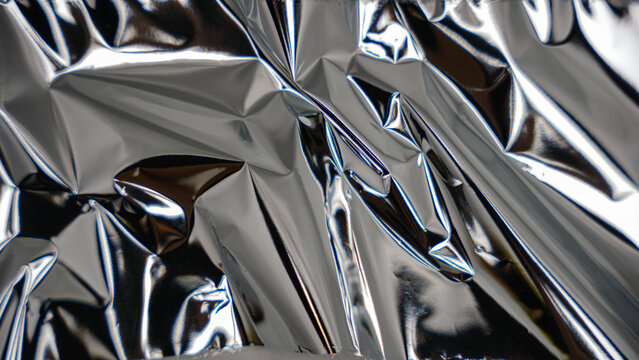 Detailed close-up of folded and creased aluminum foil creating a reflective, abstract metallic surface.