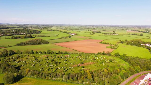 Aerial panning view, Scottish farmland showing a patchwork of green pasture, cultivated fields and hedgerows creating patterns across the rural countryside