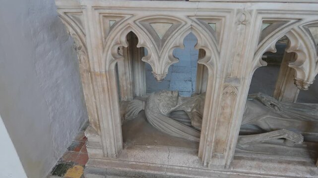 15th century cadaver tomb of John FitzAlan, 7th Earl of Arundel: a carved shrouded corpse lying beneath Gothic tracery in the Fitzalan Chapel at Arundel Castle, West Sussex, England. Slow pan down.