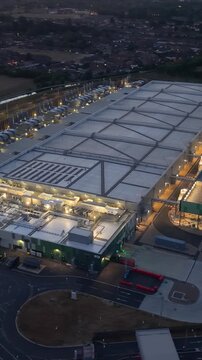 Google data centre Waltham Cross drone orbit at dusk, moving side to front with lights on, highlighting power demand, cooling load and energy efficiency questions in UK tech hub. Vertical format.