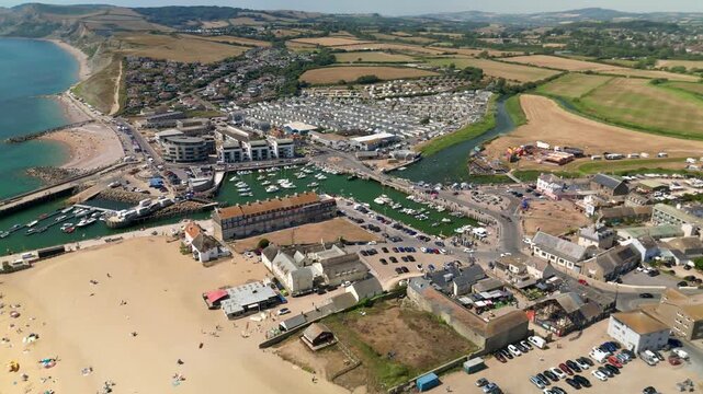Aerial drone View of West Bay in Dorset England showing harbour, marina, sandy beach, River Brit, seaside town and surrounding countryside along Jurassic Coast