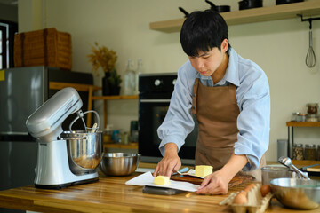 Fototapeta premium Young Asian Man Preparing Butter for Cookie Making Process in Modern Home Kitchen