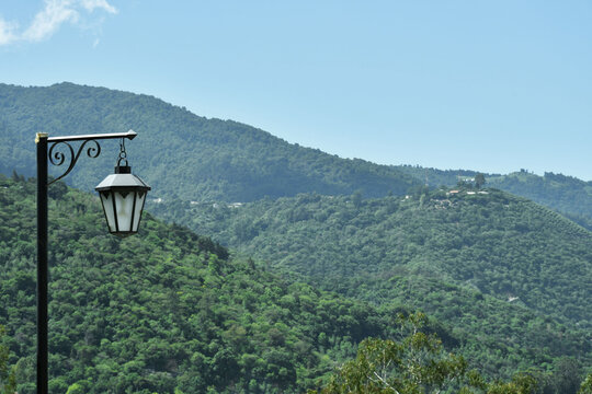 Farol antiguo, al fondo las monta&ntilde;as que rodean la ciudad de Antigua Guatemala y un cielo azul despejado.