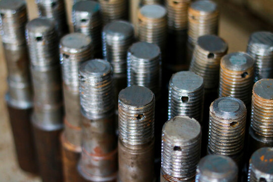 Group of threaded metal bolts standing upright in workshop, Close up of industrial steel pins and fasteners