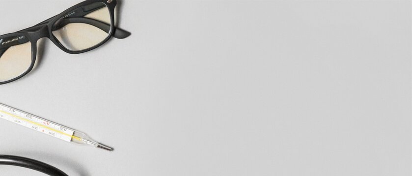 Glasses, Thermometer and Stethoscope on Gray Background with Copy Space