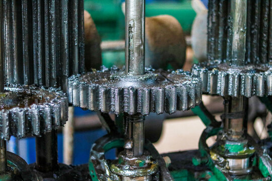 Heavy industrial metal gears covered in thick black grease, Close up shot of mechanical machine cogwheels, Factory machinery parts background