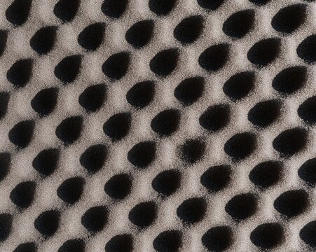 Dark charcoal grey closed-cell foam texture with a tactile pitted surface and soft shadows for protective packaging and industrial backgrounds