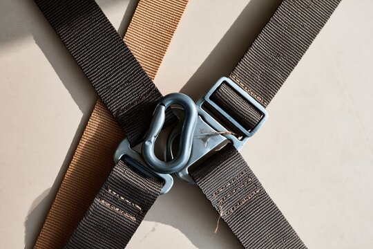 Fall-arrest harness with forged snap hook and sliding buckle, featuring woven webbing texture and metallic hardware for safety training and PPE supply