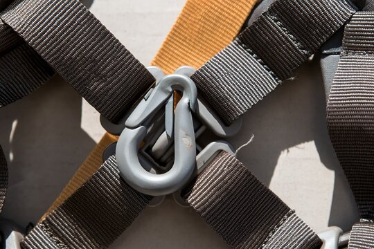 Fall-arrest harness with forged snap hook and webbing straps, featuring textured stitched seams and metallic hardware for PPE supply and safety training