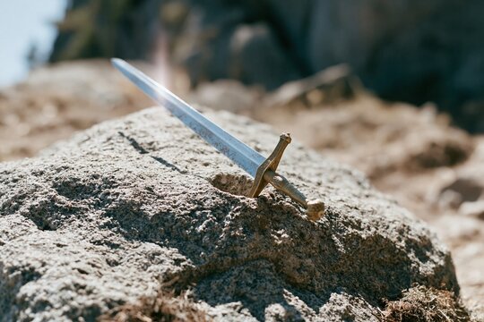 Ancient sword embedded in a rough granite boulder, featuring a weathered metal blade and ornate hilt for fantasy and mythological branding
