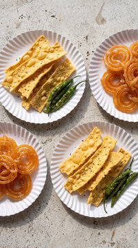 Traditional Gujarati Fafda and Jalebi on Paper Plates with Fried Green Chilies