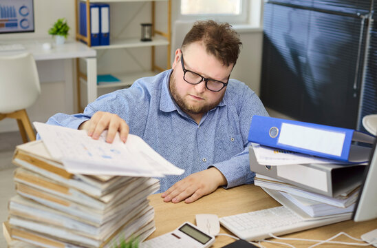 Man accountant in office doing paperwork analysis. He reviews financial documents with focus, doing review for accounting and finance tasks. Strong focus on finance review workflow today.