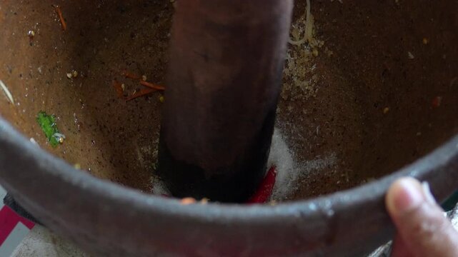 4K High angle close-up shot of red chilies and monosodium glutamate powder inside clay mortar for making Thai papaya salad, Cooking process Thai food spicy dish and street food.