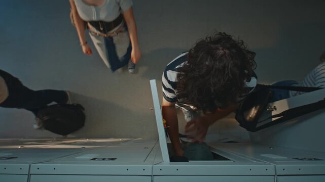 Students Opening Metal Lockers in Hallway. Curly Female Student Uses Key to Unlock Grey Locker While Male Classmate Stands Beside His Open Locker. Top View, School Life and Student Routine. Top View.