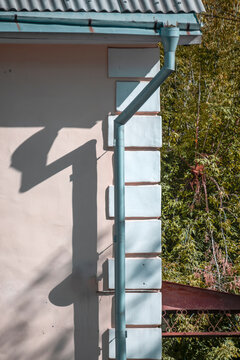 An old downpipe on the wall of a building on a summer day