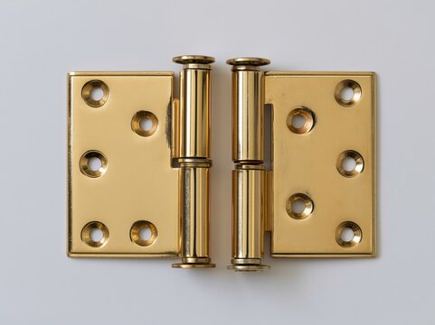 Pair of new residential door hinges laid flat on a neutral surface in bright studio light
