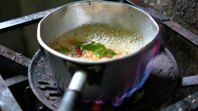 4K hot and spicy Tom Yum soup with mushrooms and herbs boiling in aluminum pot on gas stove, Authentic Thai soup Tom Yum cooking process and menu.