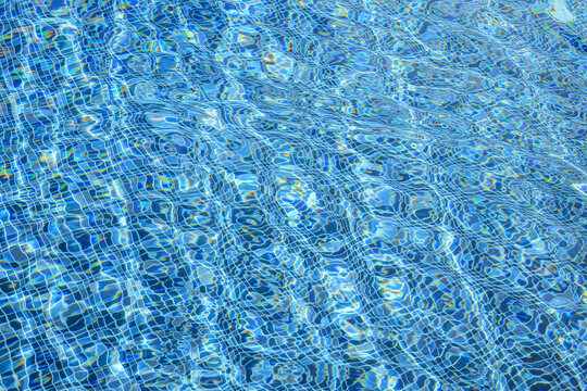 Swimming pool with blue crystal clear water surface and ripple wave background