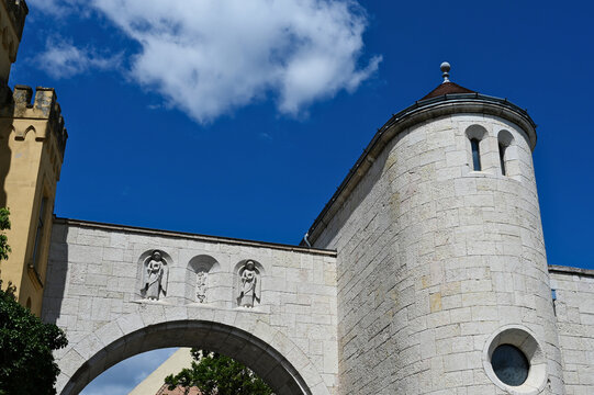 closeup of stone city gate and bastion. Veszprem, Hungary. recently renovated structure. stone sculptures in wall alcoves. sloped clay roof. round window. low angle view. architecture, travel concept