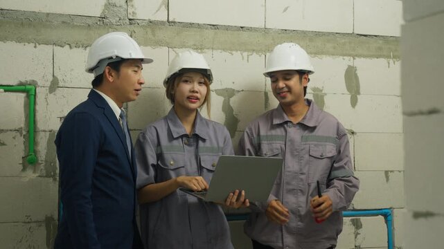 Construction worker and engineer with laptop in safety helmet having teamwork discussion at building site ensuring project progress and safety measures on unfinished construction site