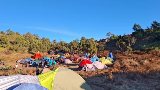 Vibrant campsite with colorful tents on sunny mountain ridge during golden hour footage.