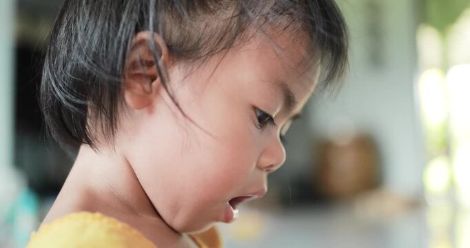 Close-up side profile of a young child focusing on an activity indoors, with warm natural light and a soft blurred background, representing childhood, learning, curiosity, and concentration