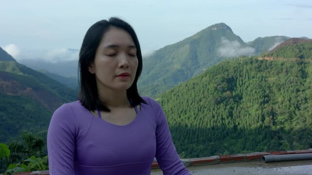 Closeup of woman meditating in Easy neutral relaxed Pose with mountain landscape behind