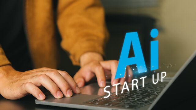 Close-up of person's hand typing on laptop keyboard with AI start-up icon