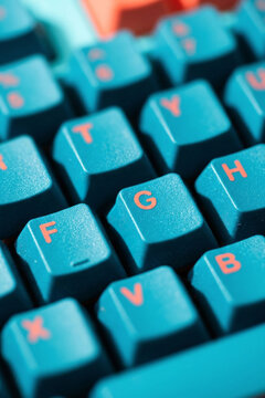 Close up of a teal mechanical keyboard with orange letters