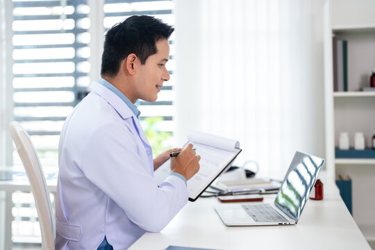 Doctor using a laptop .Physician working with technology in office, wearing a white lab coat and a stethoscope.