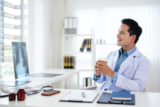 Asian male GP doctor looking away with friendly smile, relish his professional success, feel satisfied with career, thinks about future achievements.