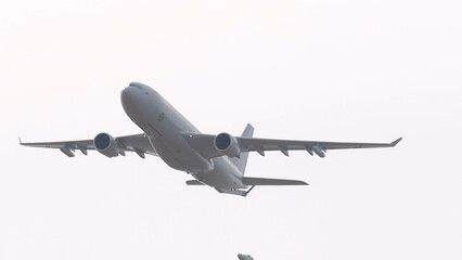Fototapeta premium Large Military Transport Jet Flying Through Overcast Sky