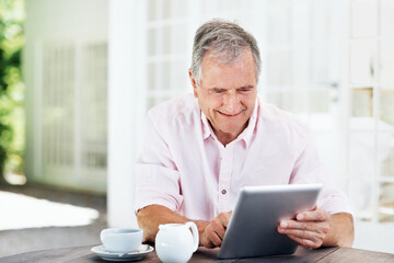 Fototapeta premium Reading, coffee and tablet with old man in home for retirement fund savings, pensioner asset and budget. Tax return, drink and loan approval with senior person in apartment for online finance