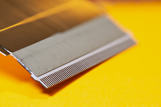 Flat flexible cable connection on yellow background, focus stacked image.