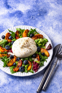 Delicious salad with burrata cheese grilled peaches and blueberry