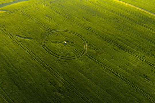 Aerial view of a circular pattern in a vibrant green agricultural field with a small white marker at the center in Chvalkovice, Hradec Kralove Region, Czechia.