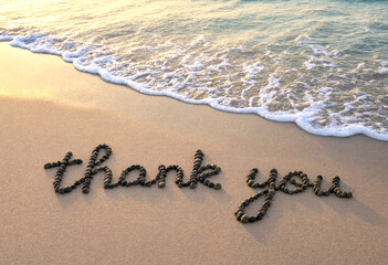 Fototapeta premium Heartfelt thank you message beautifully written in pebbles on sandy beach near ocean waves