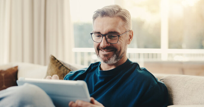Smile, man and reading at house with tablet, social media and browsing online for latest movies. Happy, mature person and relax in lounge with tech, internet search and streaming for film watchlist