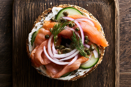 A classic lox bagel, featuring smoked salmon and an array of crisp vegetables, laid flat and photographed overhead
