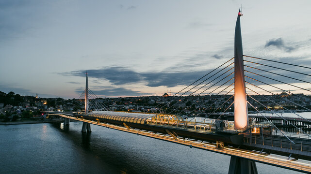 Aerial view of the Golden Horn metro bridge spanning the water with illuminated pylons and the city skyline in the background at dusk in Beyoglu, Istanbul, Turkiye.