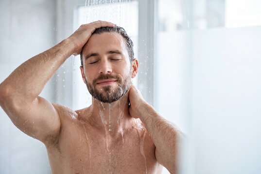 Handsome man with beard enjoying a refreshing shower in a bright modern bathroom