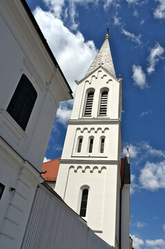 church bell towers in elevation view in the city of Veszprem in Hungary. white stucco exterior wall finish. steep sloped roofs. Christian cross on top. travel, tourism, architecture, religion concept